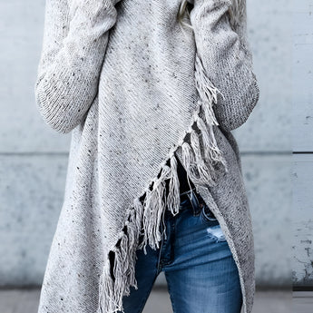 
A woman wearing a chunky turtleneck sweater in a winter fashion setting, paired with taupe ankle boots. She is seated, showcasing the outfit's style and detail against a simple background. The sweater's texture and design are highlighted, emphasizing its suitability for cold weather.