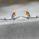 Colorful bird-shaped earrings featuring intricate designs of European robins perched on twigs, crafted in metal.