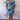 
A multicolor knee-length summer dress featuring a vibrant wave pattern and V-neck design, worn by a person. The dress is complemented by matching footwear, highlighting a fashionable and stylish look.