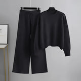 Black Cozy Cream Knit Sweater & Wide-Leg Pants Set on a clothes hanger, featuring long sleeves and a comfortable, loose fit.