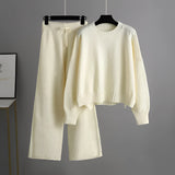 Cozy cream knit sweater and wide-leg pants set on a clothes hanger, featuring a round neck and long sleeves, perfect for winter loungewear.