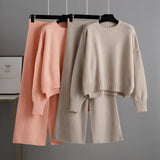 Cozy cream knit sweater with long sleeves and a wide neck, paired with matching wide-leg pants, displayed on a clothes hanger.