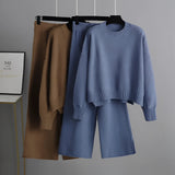 A cozy cream knit sweater and wide-leg pants set hanging on a clothes hanger, showcasing winter loungewear with long sleeves and a comfortable fit.