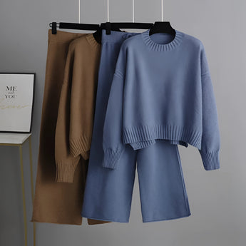 A cozy cream knit sweater and wide-leg pants set hanging on a clothes hanger, showcasing winter loungewear with long sleeves and a comfortable fit.
