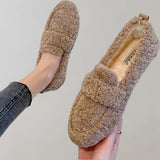 Light grey cozy fleece slippers for women, featuring a soft plush design and an anti-slip sole. The image shows a close-up view of the slippers, highlighting their snug interior and fashionably simple pattern. A hand is visible, possibly adjusting the slipper.