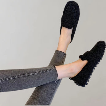 Cozy fleece slippers in light grey, shown on a woman's foot with soft plush material and an anti-slip sole.