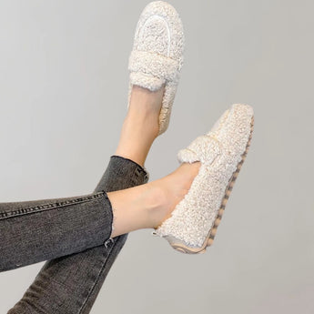 Cozy fleece slippers in light grey, shown on a woman's foot, highlighting their soft plush material and anti-slip soles.