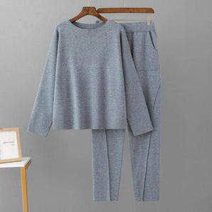 Cozy gray women's fleece loungewear set featuring a sweatshirt and pants, displayed on a clothes hanger. The set includes a long-sleeve top with a subtle collar, made from soft, wool-like material, showcasing a simple yet stylish design.