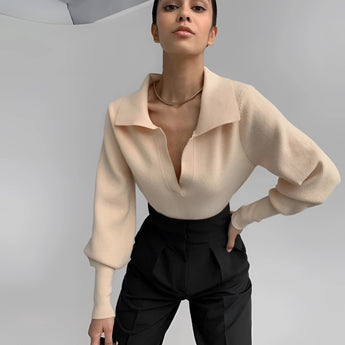 
A person wearing a cream high-neck cropped sweater featuring stylish back detail. The sweater has long sleeves and a fitted waist, with the model standing and showing the back design.