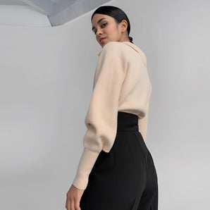 Cream high-neck cropped sweater featuring stylish back detail, worn by a person showcasing the arm and shoulder, highlighting the sweater's fit and design around the neck, waist, and sleeves.