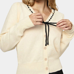 Cream lightweight V-neck cardigan with a tie closure, worn by a person with sunglasses. The cardigan features long sleeves and is styled over a dress shirt, emphasizing a casual chic look.