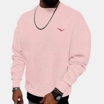 Men's crewneck sweatshirt in rose pink, featuring a minimalistic urban style with a small bird logo on the chest. Model is shown wearing the sweatshirt, highlighting the comfortable fit with long sleeves and a crew neckline. The 3XL size offers a relaxed and casual look.