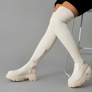 Cream ribbed knit knee-high boots with chunky soles, showcasing a winter-ready design that fits snugly around the leg, extending up to the knee.