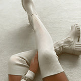 White cream ribbed knit knee-high boots with a chunky sole, designed for winter footwear. The boots are displayed standing upright, highlighting the ribbed texture and knee-high length.
