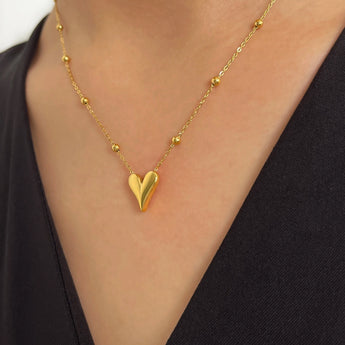 Dainty 18K Gold Heart Pendant Necklace worn around a woman's neck, highlighting the elegant romantic design against her chest and shoulder.