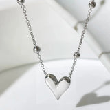 A dainty silver heart pendant necklace on a delicate chain, displayed against a neutral background, highlighting its elegant and romantic design.