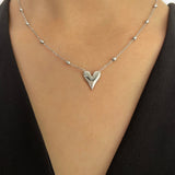 Close-up view of a woman wearing a dainty 18K gold heart pendant necklace on her neck, showcasing elegant and romantic jewelry design.