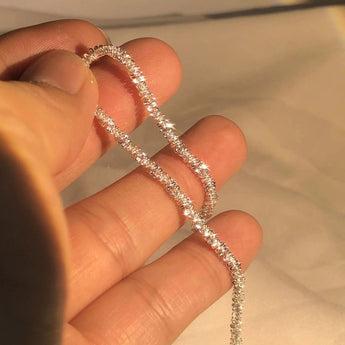 Elegant minimalist silver bracelet featuring a dainty diamond, worn on a wrist, suitable for bridal occasions.