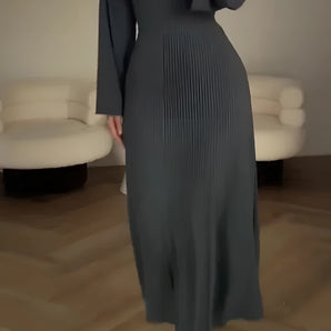 Dark green pleated A-line dress with bishop sleeves, featuring a formal evening wear design and worn by a person with visible hair and a slender waist.