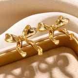 Gold and bow-shaped earrings featuring a combination of natural materials and metal, styled in a macro photography setting.