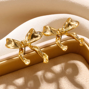 Gold and bow-shaped earrings featuring a combination of natural materials and metal, styled in a macro photography setting.