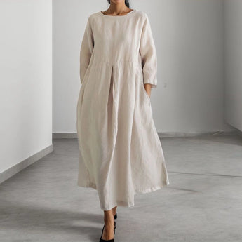 Eco-friendly oatmeal linen maxi dress in apricot color, featuring a minimalist loose fit design with an XL size. The dress showcases a round neck, long sleeves, and a flowing one-piece silhouette that reaches to the knees, suitable for formal events.