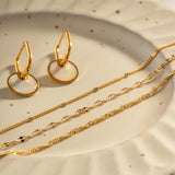 Elegant 18K layered gold multi-strand necklace, delicate fashion jewelry with a natural material finish, featuring circular metal elements.