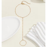 Elegant adjustable gold chain bracelet with minimalist circle charm on beige background.