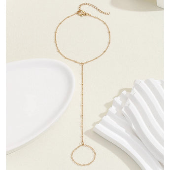 Elegant adjustable gold chain bracelet with minimalist circle charm on beige background.