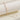 Elegant adjustable gold chain bracelet with minimalist circle charm, displayed on a beige surface with natural twig accents.