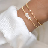 A hand wearing an elegant adjustable gold bracelet adorned with a pearl, displayed on a wrist, showcasing luxury jewelry.