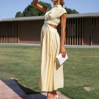 Elegant black midi dress with a stylish back cutout, designed as evening wear, featuring long sleeves and a fitted waist, modeled outdoors with a natural backdrop of trees and sky.