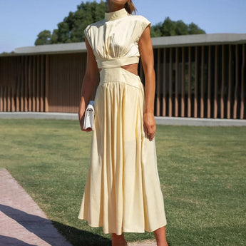 Elegant back-cutout black midi dress with sleeves, designed for evening wear, displayed outdoors against a backdrop of grass and trees.