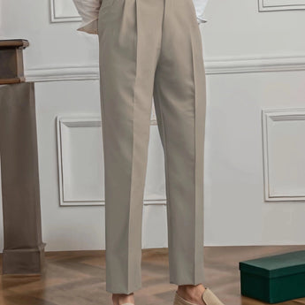Elegant beige high-waisted pleated trousers for women, designed for office wear. The trousers are displayed in a neutral setting, highlighting the soft beige color and the sophisticated pleated design around the waist and thighs.