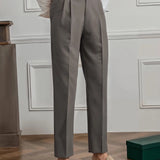 Elegant beige high-waisted pleated trousers for women, shown in a charcoal gray variant, suitable for office wear. The image focuses on the waist and leg areas, highlighting the neat pleats and tailored fit. The trousers are paired with a dress shirt, adding to the professional look.