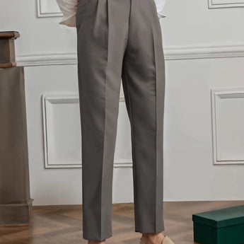 Elegant beige high-waisted pleated trousers for women, shown in a charcoal gray variant, suitable for office wear. The image focuses on the waist and leg areas, highlighting the neat pleats and tailored fit. The trousers are paired with a dress shirt, adding to the professional look.