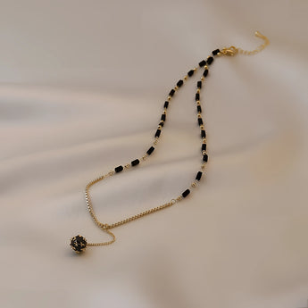 Elegant black gemstone pendant necklace with gold chain, luxury women's jewelry displayed on a white background.