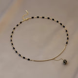 Elegant black gemstone pendant necklace on a gold chain, luxury women's jewelry featuring a polished stone set in a metal frame.