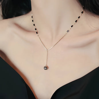 Elegant black gemstone pendant necklace with gold chain displayed on white background.