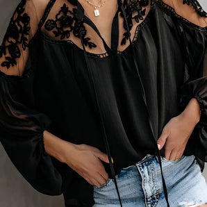 
A stylish black lace blouse featuring sheer sleeves and intricate floral embroidery, shown on a model.
