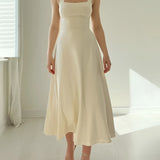 Elegant black midi dress with a square neckline and pockets, featuring a fitted bodice and flowing skirt.