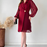 Elegant black pleated mini dress with long sleeves, tailored for an office chic look, featuring a fitted waistline and a graceful neckline.