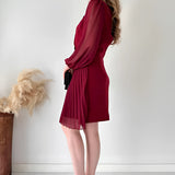 Elegant black pleated long sleeve mini dress featuring a fitted waist and knee-length hem, perfect for an office chic look.