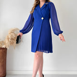 Elegant blue pleated long sleeve mini dress styled for an office chic look, worn by a model.