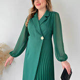 Elegant black pleated mini dress with long sleeves, featuring a chic office style, worn by a woman who is smiling and posing with her hand on her waist.