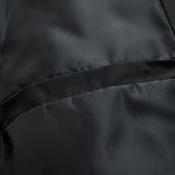 Elegant black silk fabric with a smooth, glossy texture displayed in a close-up shot, showcasing subtle patterns and shades, resembling the sheen of luxury textiles.