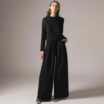 Elegant black wide-leg palazzo jumpsuit with long sleeves, high waist, and boat neck design.