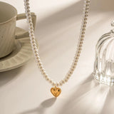 Elegant bridal pearl choker necklace with a gold heart charm, featuring white pearls and a delicate chain, perfect for a romantic gift.