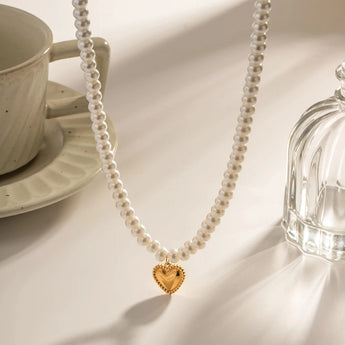 Elegant bridal pearl choker necklace with a gold heart charm, featuring white pearls and a delicate chain, perfect for a romantic gift.