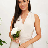 Elegant cream backless evening gown with a bow, suitable for a wedding guest, featuring delicate shoulder and neck design, complemented by elegant bridal accessories and a joyful smile.